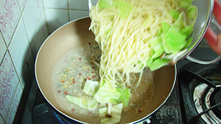 8のアンチョビソースにパスタを加え、中火で全体を炒め合わせている