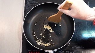 フライパンにオリーブ油とにんにくを入れて焦がさないように弱火で炒めている