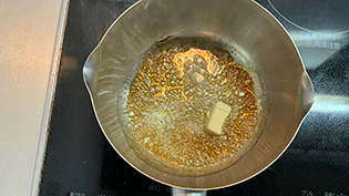 砂糖が茶色に色づき始めたら、無塩バターを入れて鍋を振りながら溶かしている