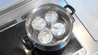蒸気のたった蒸し器に茶碗を入れる