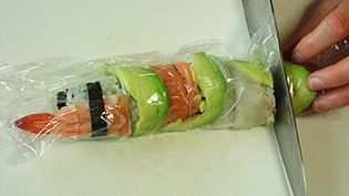 ご飯が崩れないように、ラップを巻いたまま切っているところ